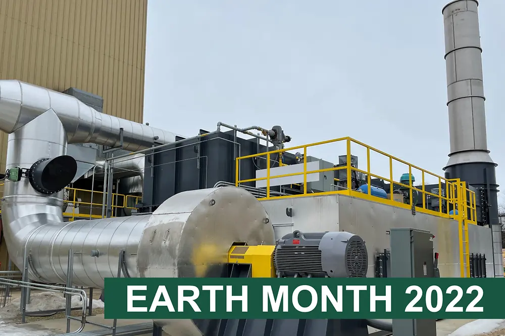 Machinery for reducing emissions outside building with 'Earth month 2022' text on a green bar