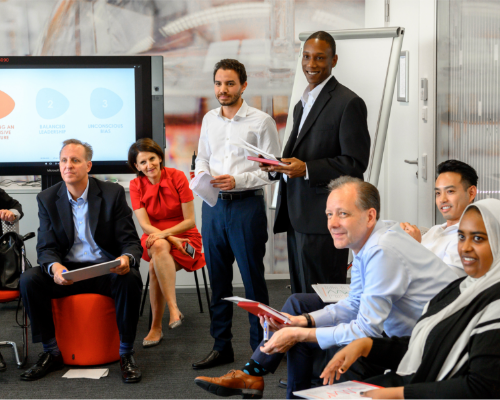 Ett mångsidigt Henkel-team sitter tillsammans på en workshop och tittar in på talaren