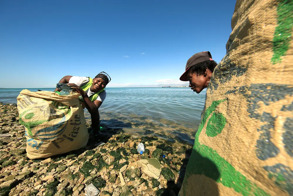塑料銀行項目：兩個人在海灘上收集塑料