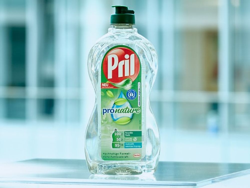 Eine Flasche des Geschirrspülmittels Pril Pro Nature steht auf einem transparenten Tisch.