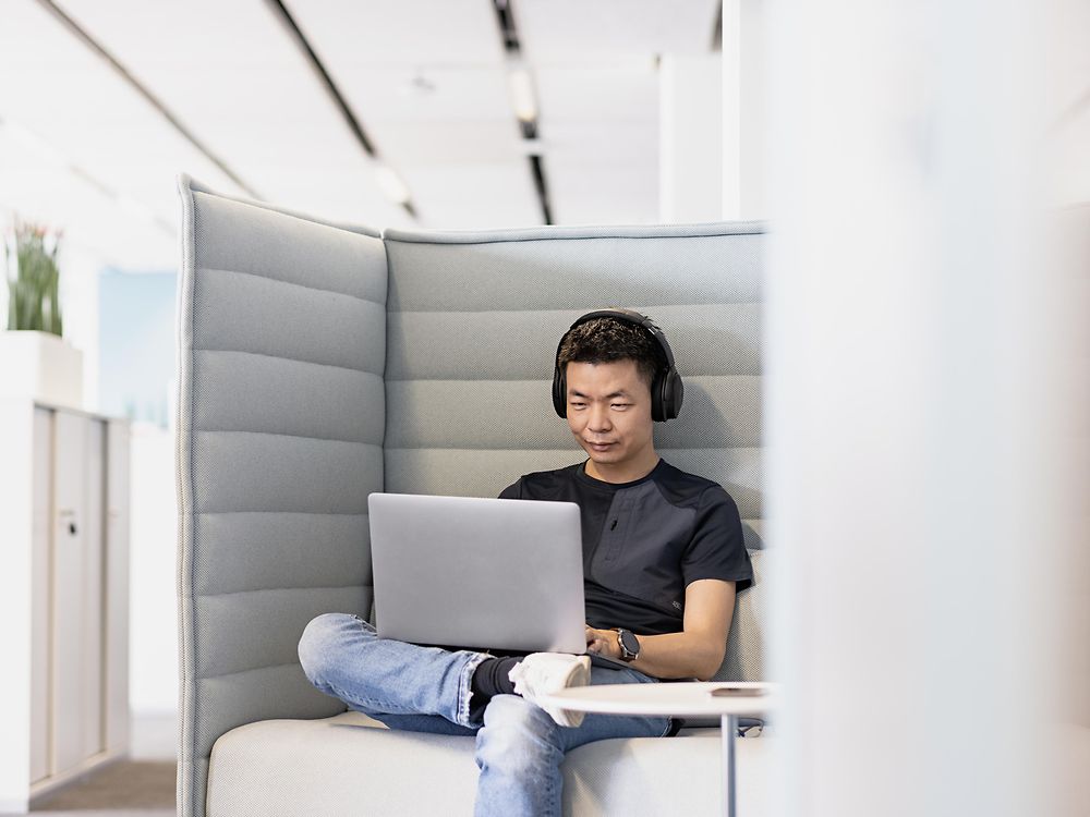 Zaposlenik Henkela sa slušalicama radi koncentriran na svom prijenosnom računalu. 