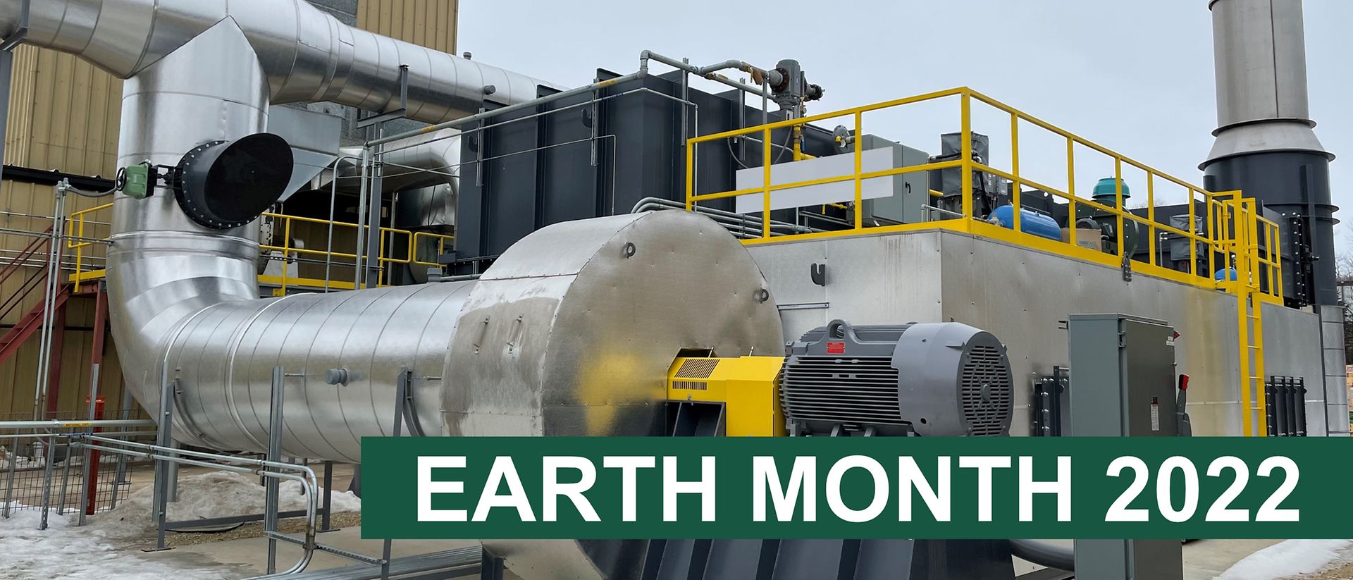 Machinery for reducing emissions outside building with 'Earth month 2022' text on a green bar