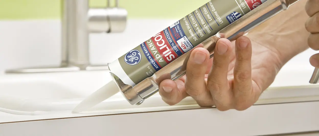Person holding tube of GE-branded sealant