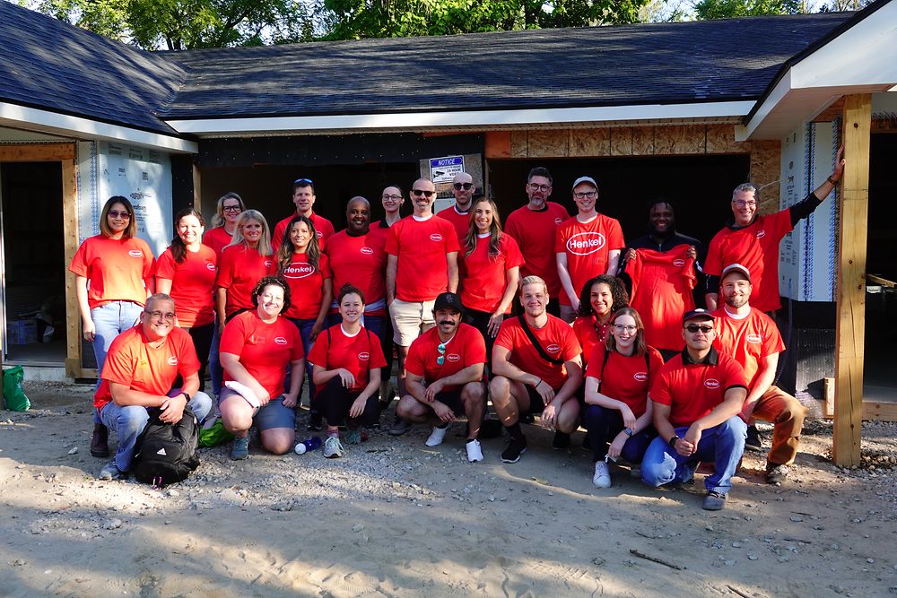 A group of people wearing red shirts in front of a house under construction