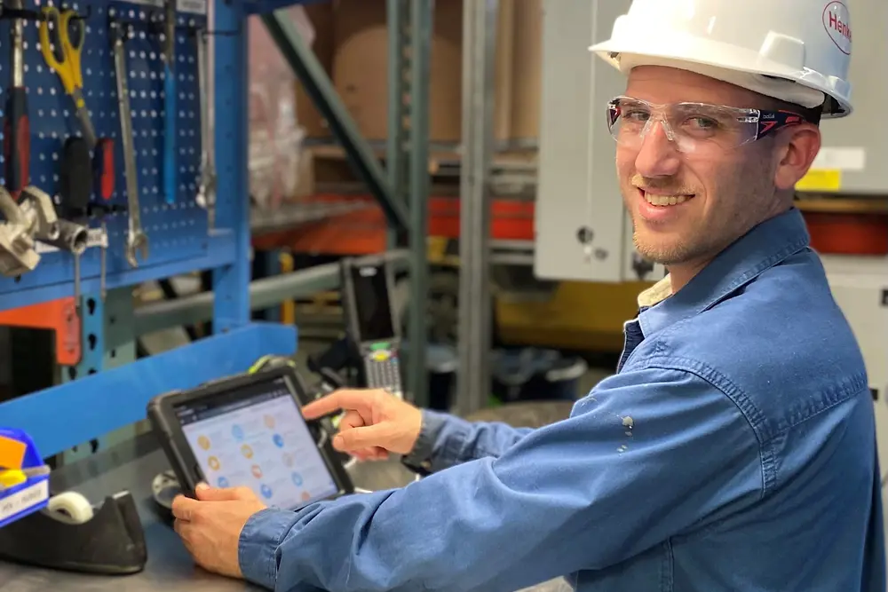 Employee wearing hard hat and holding tablet