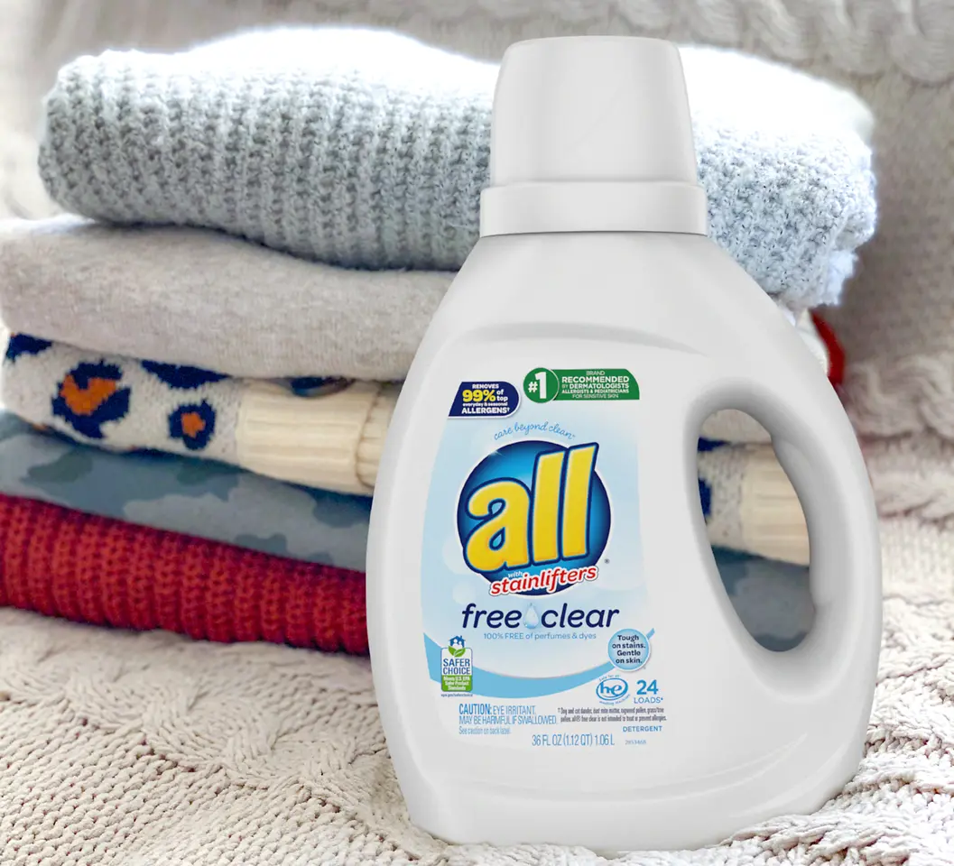 An 'all' brand detergent product is sitting in front of stacked and folded laundry. 