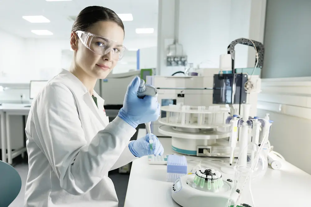 一位穿著白大褂，戴著護目鏡女科學家正在實驗室裏做實驗。