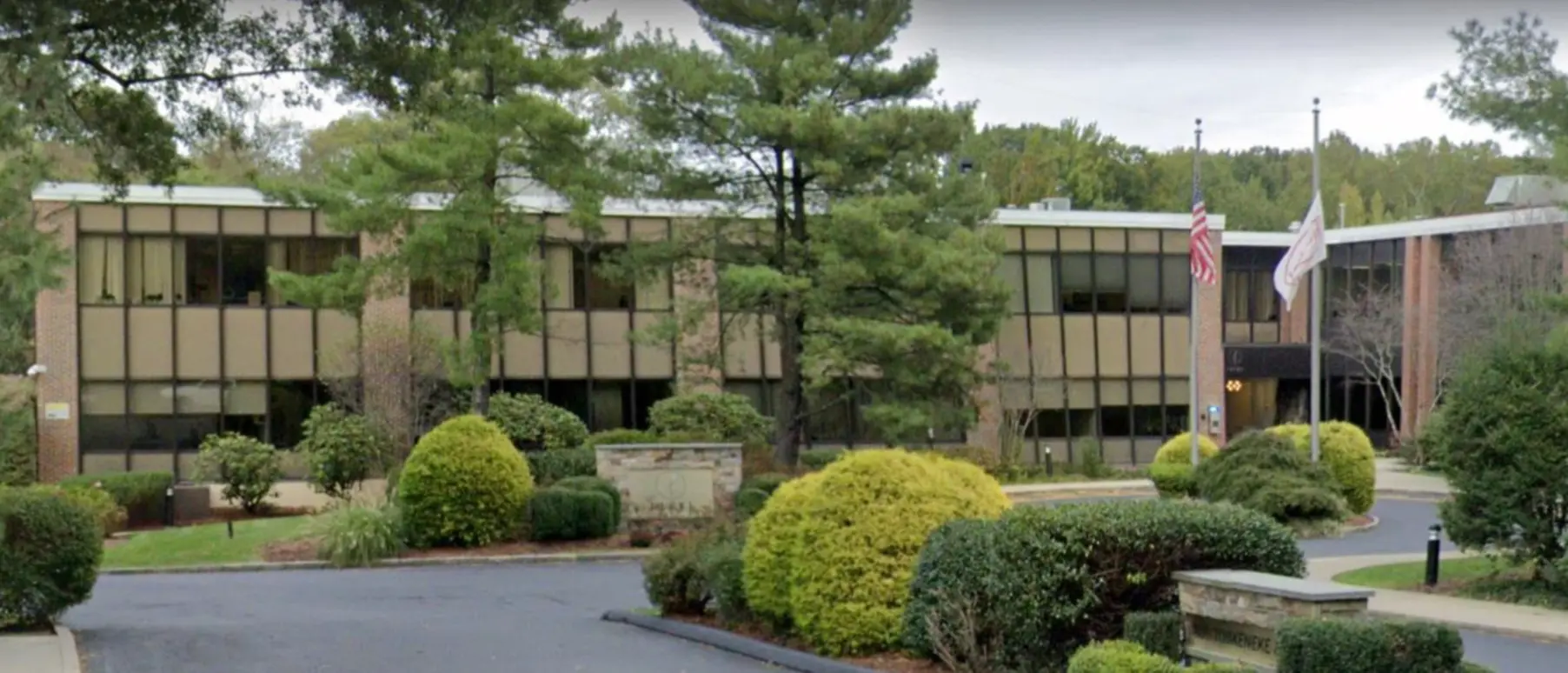 Building exterior with greenery and U.S. flag in front