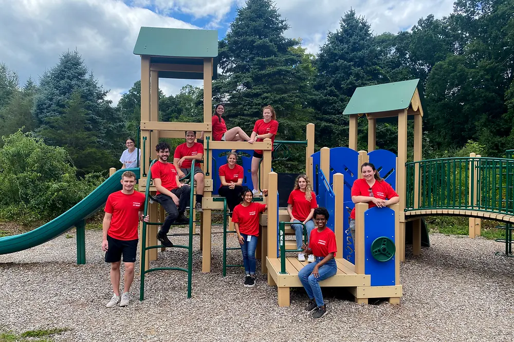 Henkel employees in red t-shirts pose in front of a playground.