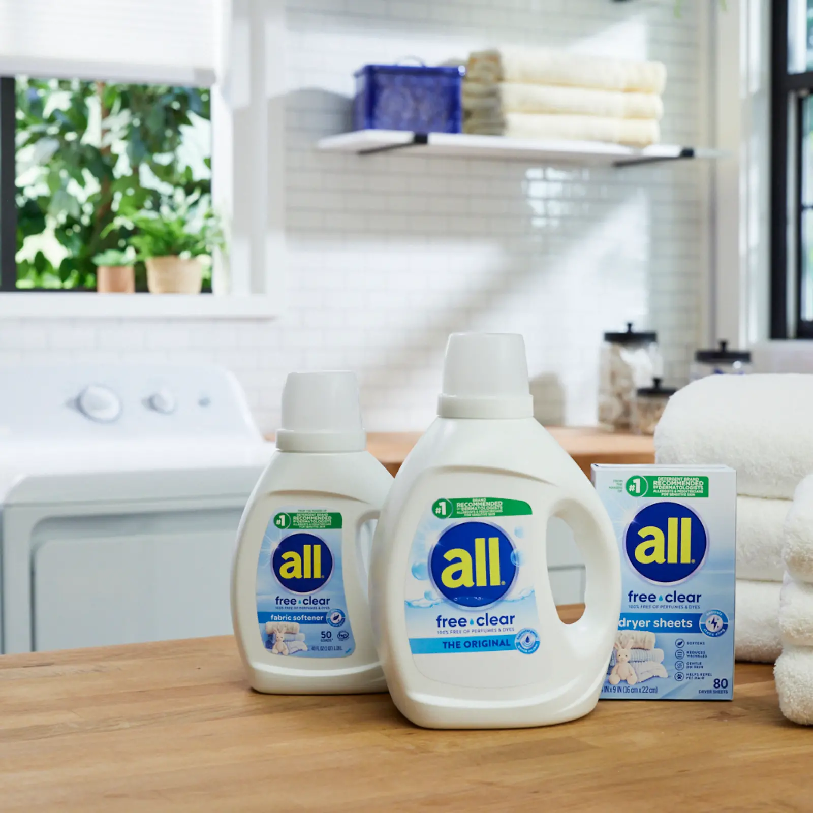 Woman holds child in a laundry room, using a bottle of all free clear detergent