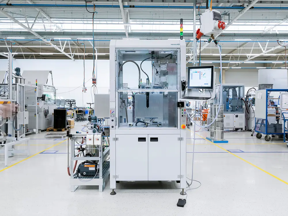 Large white machine in the center of a busy manufacturing facility