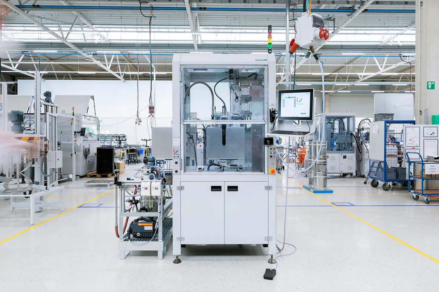 Large white machine in the center of a busy manufacturing facility