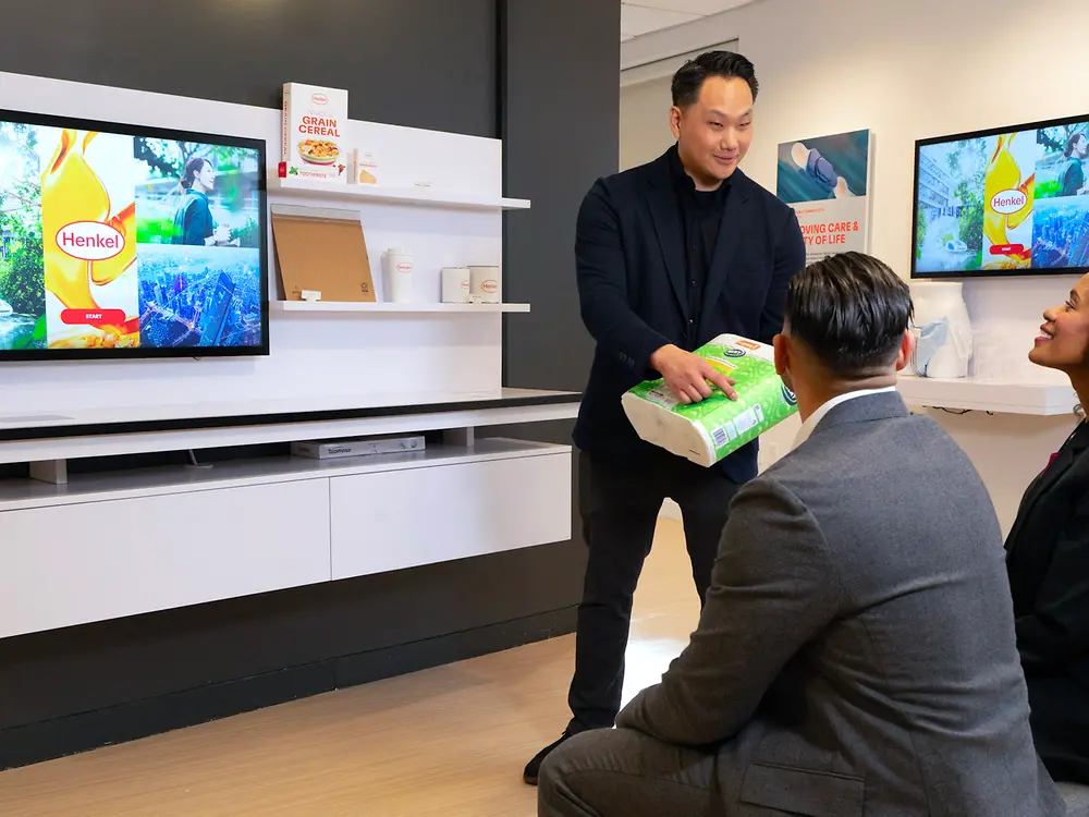 A customer experience tour guide presents application examples from Henkel Adhesive Technologies to two customers at the Technology Center Bridgewater.