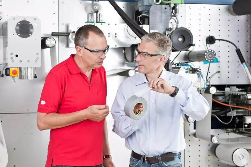 A photo of Henkel employees holding a roll of tape.