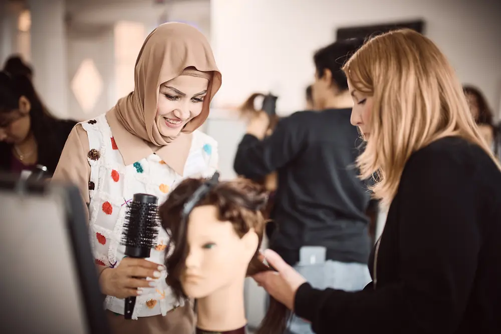 Two women are styling a training mannequin as part of the Shaping Futures program.