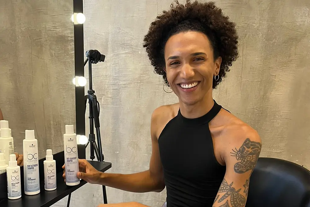 Guina is sitting in salon chaire and smiles into the camera.