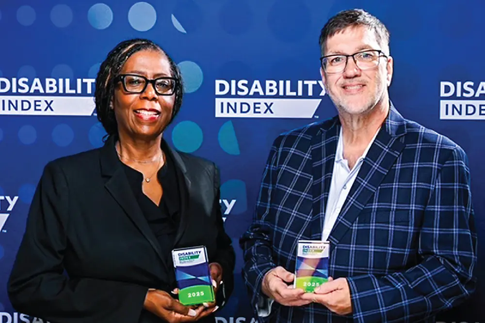 Angie and Bill holding awards in front of them against a blue backdrop with the <i>Disability Index</i> logo repeated.