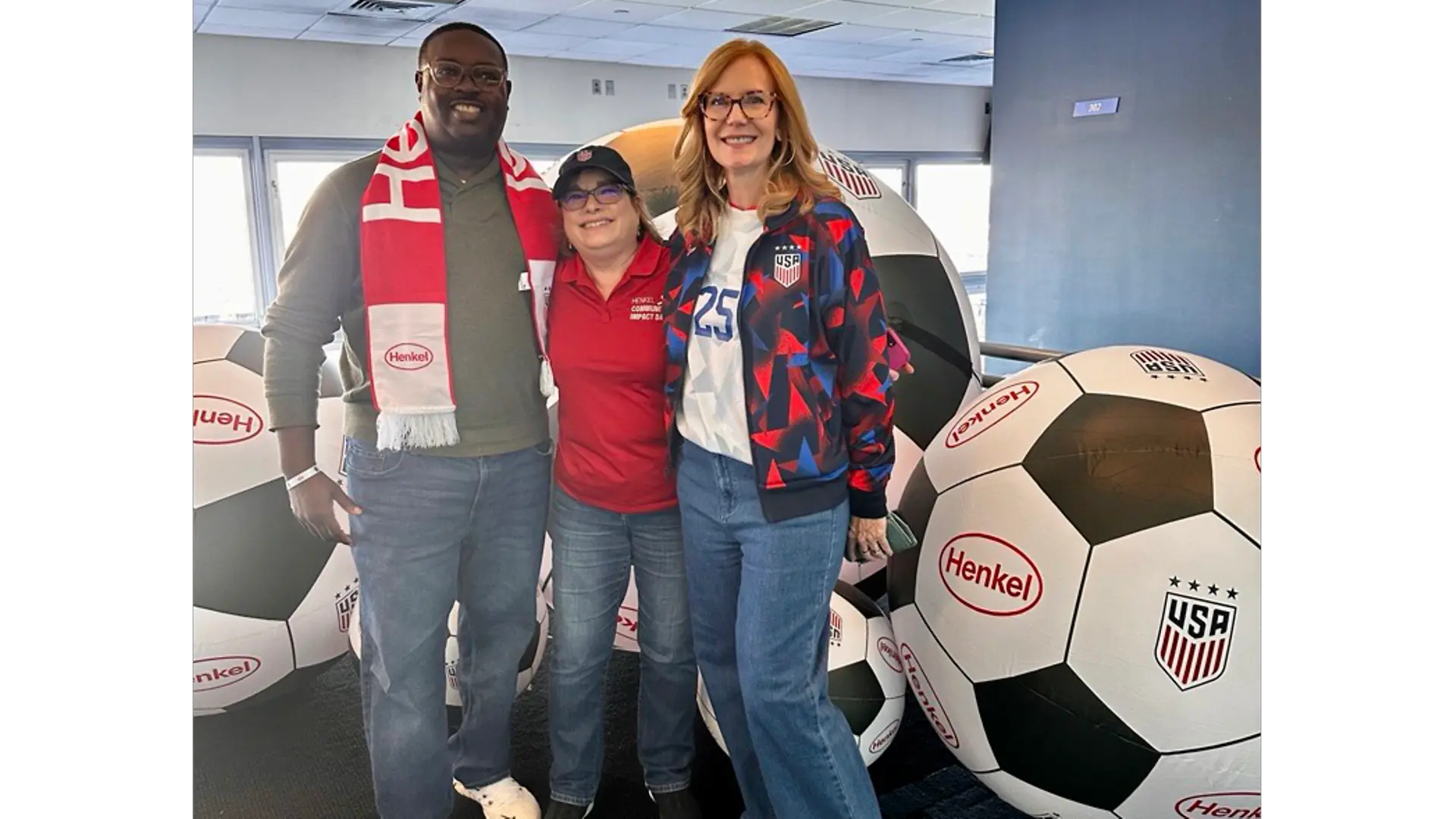 Three people standing in front of oversized soccer balls printed with Henkel logo and U.S. Soccer crest.