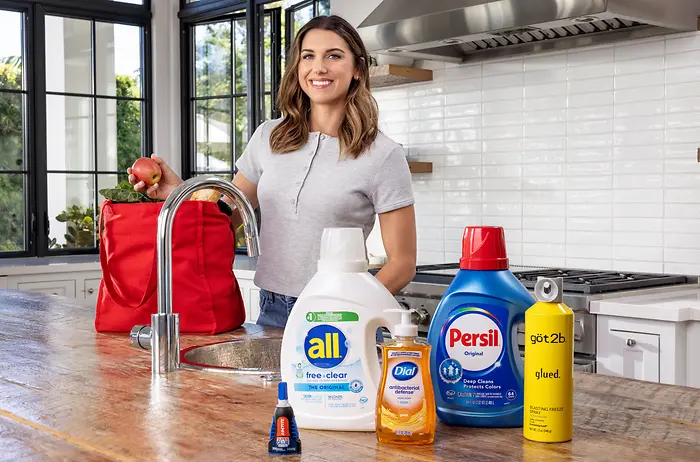 Alex Morgan in kitchen with Henkel products including all free clear, Dial, Persil, got2b and Loctite.