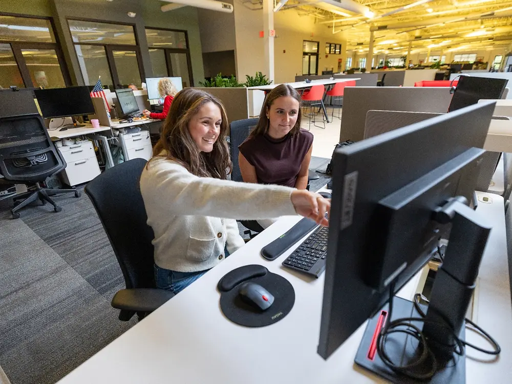 Two employees work at a computer.