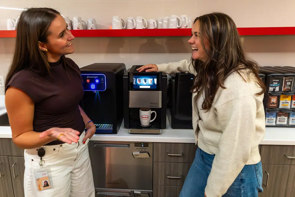 Two Henkel employees have a conversation over the coffee machine.