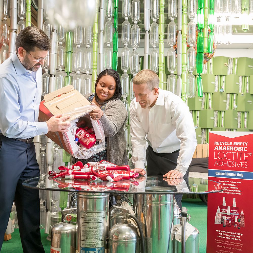 Rhandi Goodman demonstrating how to handle the recycling boxes to her project partners from Henkel, Simon Mawson (left) and Chris Stanford
